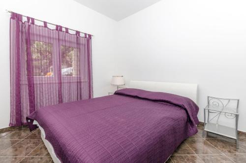 a bedroom with a purple bed and a window at Apartments Beba55 m in Primošten