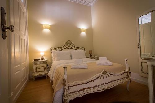 a bedroom with a white bed with two towels on it at São Domingos Flowers Apartments in Porto