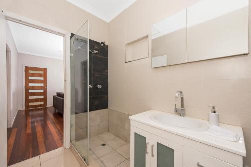 a white bathroom with a sink and a shower at 2 bedroom cottage in Townsville