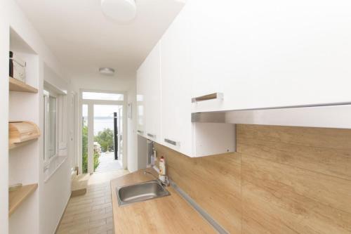 cocina con paredes blancas, fregadero y suelo de madera en House Anica, en Starigrad-Paklenica