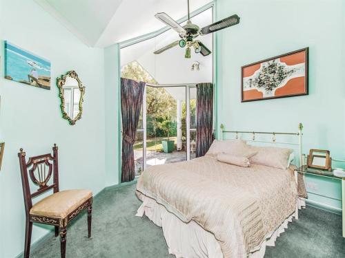 a bedroom with a bed and a chair and a window at Noosa Hinterland Spectacular Boutique Guesthouse in Cooran