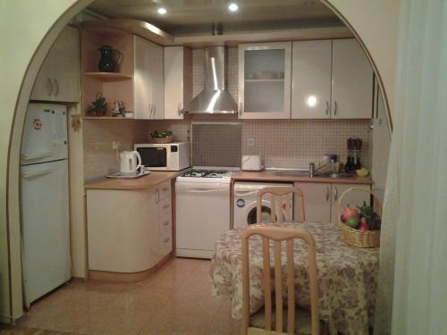 eine Küche mit weißen Geräten und einem Tisch mit Stühlen in der Unterkunft Metro SAHIL Seaside Centr in Baku