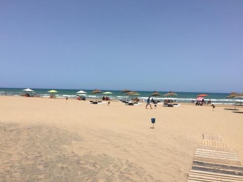 a beach with umbrellas and people on the beach at Perle Orientale Saidia Appart Rénové vue sur jardin et sur mer in Saidia 