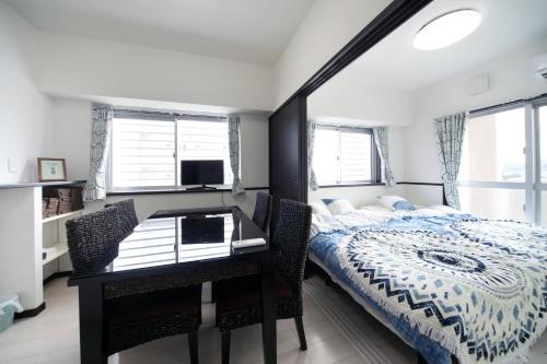Schlafzimmer mit einem Bett und einem Schreibtisch sowie einem Bett und Fenster in der Unterkunft EX Itoman Apartment 701 in Itoman