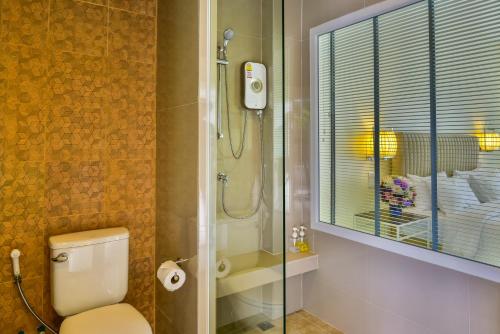 a bathroom with a shower and a toilet and a glass door at Southgate Residence Hotel - SHA Certified in Chumphon