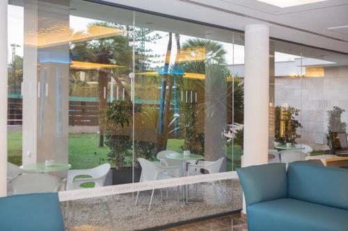 a restaurant with white chairs and tables and windows at Hotel Luxor in Playa de Palma