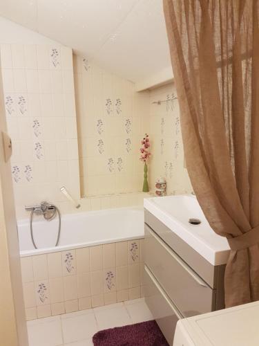 een badkamer met een wit bad, een wastafel en een douche bij Maison Luvy in Sundhoffen