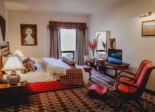 奎达Quetta Serena Hotel的一间卧室，配有一张床、一张桌子和一把椅子