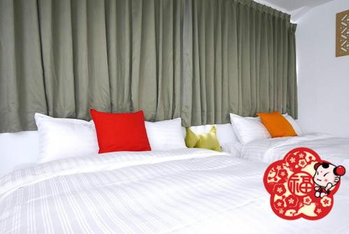 台南的住宿－大福好，一间卧室配有两张白色床和色彩缤纷的枕头