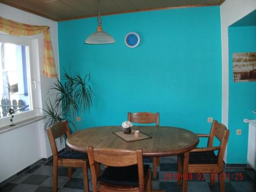 einen Esstisch mit Stühlen und eine blaue Wand in der Unterkunft Ferienwohnung In Vino Veritas in Neumagen-Dhron