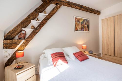 een slaapkamer met een wit bed en 2 rode kussens bij Beaune Sweet Home in Beaune
