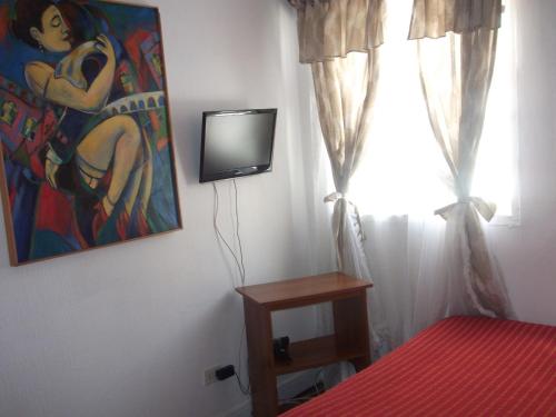 a bedroom with a tv and a painting on the wall at Mediterraneo B&B in Viña del Mar