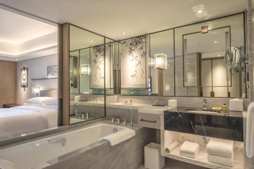 杭州市にあるGrand Hyatt Hangzhouのバスルーム(バスタブ、シンク2台、ベッド1台付)