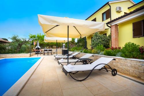 a group of chairs and an umbrella next to a pool at Apartmani Hrelja in Labinci