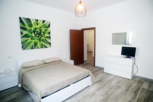 een witte slaapkamer met een bed en een televisie bij Casa Di Vita in Pescara