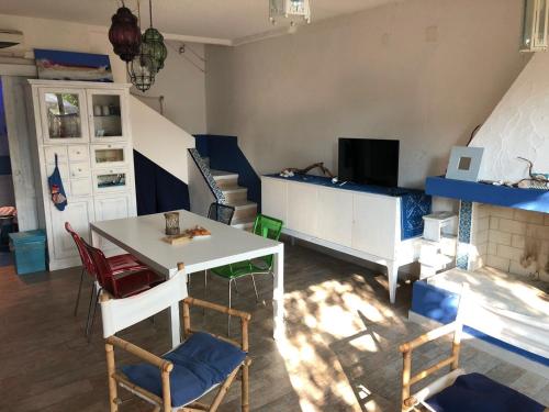 een woonkamer met een tafel en stoelen en een televisie bij Villa stella di mare in Capitana