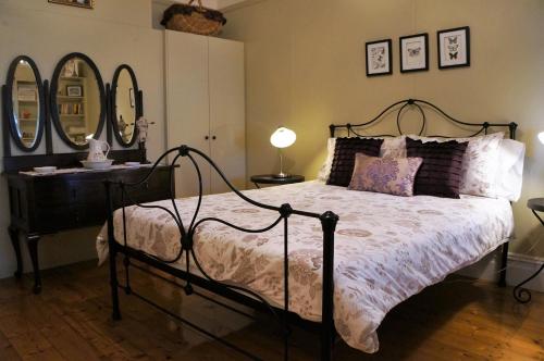 a bedroom with a bed and a dresser and mirrors at Delightful Cottage in Queenscliff