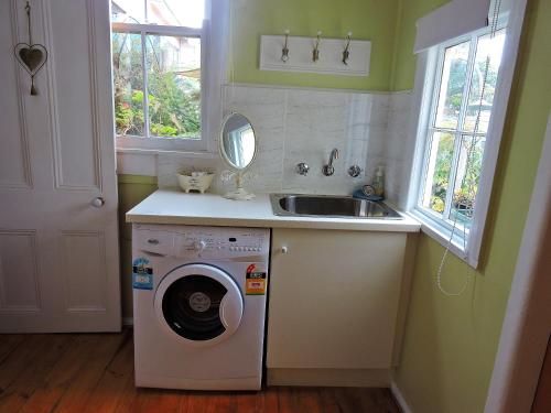 a kitchen with a washing machine and a sink at Delightful Cottage in Queenscliff