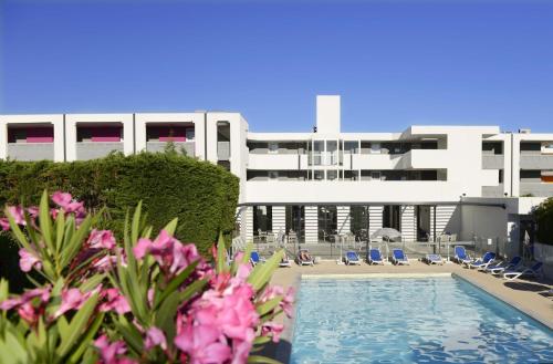 - une vue sur un bâtiment doté d'une piscine et de fleurs roses dans l'établissement Résidence Odalys Aqualia, à Balaruc-les-Bains