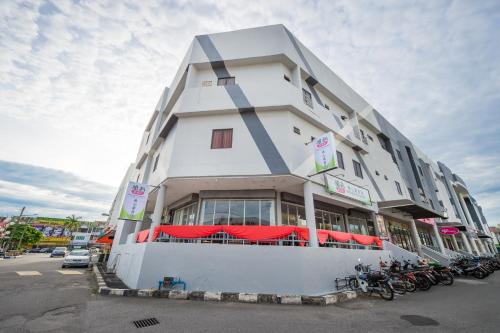 a large white building with motorcycles parked in a parking lot at Northern Lodge Hotel in Sungai Petani