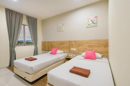 スンガイ・プタニにあるNorthern Lodge Hotelのピンクの枕が備わるホテルルームのベッド2台