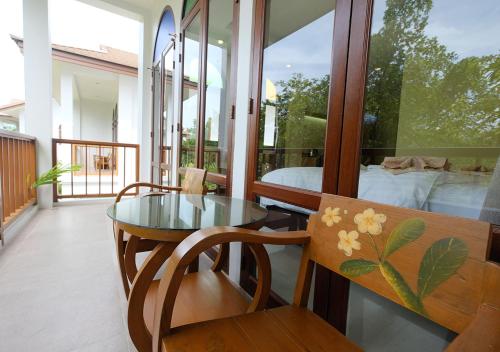 a glass table and chairs in a room with a bedroom at Baan Imm Sook Resort in Chao Lao Beach