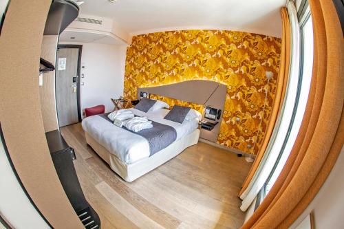 a bedroom with a bed and a yellow wall at Hôtel Hor Europe in Paris