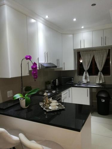 a kitchen with white cabinets and a black counter top at Pongola Road Self Catering Accommodation in Uitenhage