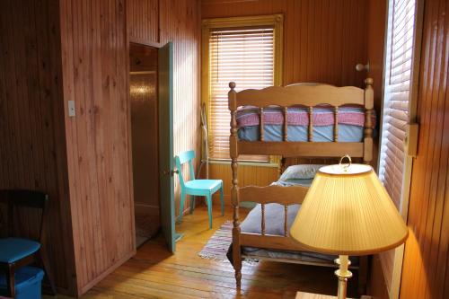 1 dormitorio con litera, mesa y lámpara en Auberge du Café chez Sam, en Baie-Sainte-Catherine