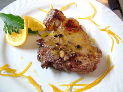 a plate of food with a piece of meat and orange slices at Locanda Il Gallo in Greve in Chianti