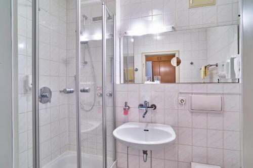 a white bathroom with a sink and a shower at Hotel Lindenhof in Kellberg