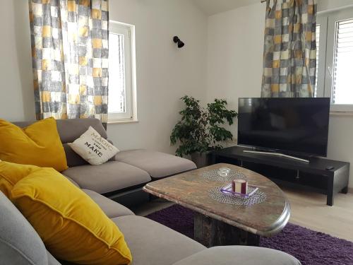 ein Wohnzimmer mit einem Sofa, einem Tisch und einem TV in der Unterkunft Apartments Krizanac in Trogir