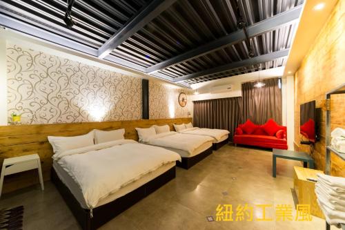 a room with three beds and a red couch at 羅東夜宿 in Luodong