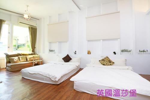 two beds in a room with white walls and wooden floors at 羅東夜宿 in Luodong