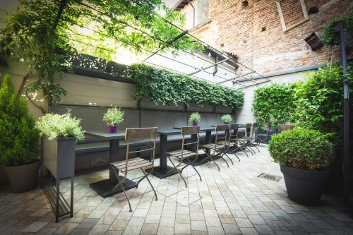 a patio with a long table with chairs and plants at Piccola Torre Maison in Vigevano