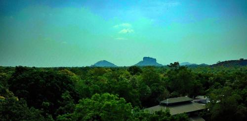 a view of a forest with mountains in the background at Sigiriya Lahiru Homestay in Sigiriya