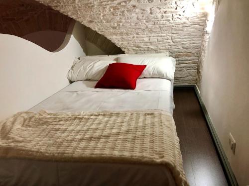a small bed with a red pillow on it at L'Orecchietta in Ruvo di Puglia