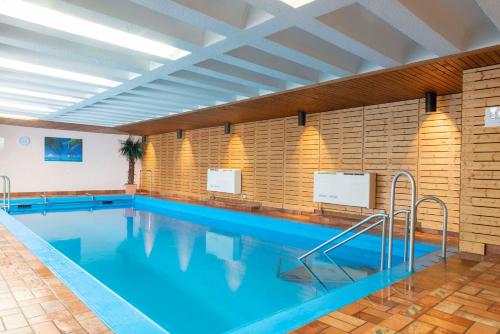 a large swimming pool with blue water in a building at Kurgarten-Hotel in Wolfach