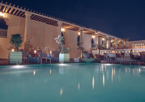 a large swimming pool at night with chairs and tables at Narendra Bhawan in Bikaner