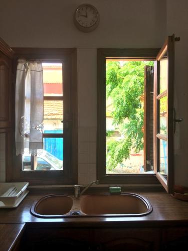 a kitchen with a sink and two windows at Ammouliani Captain's House in Ammouliani