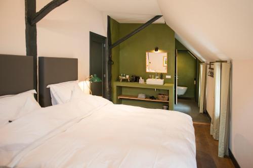 a bedroom with a white bed and a green wall at De Heeren van Tuil in Tuil