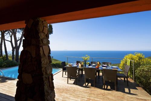 a dining table on a deck with a view of the ocean at Tenuta Delle Ripalte in Capoliveri