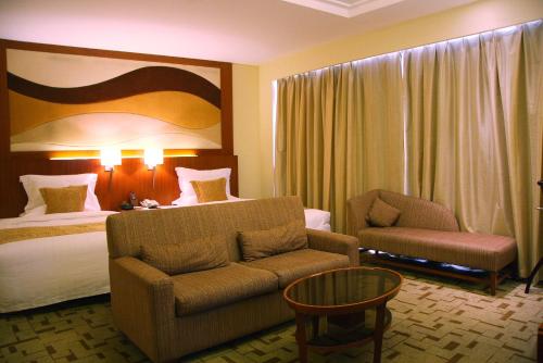 Pokój hotelowy z łóżkiem, kanapą i krzesłem w obiekcie Jian Guo Garden Hotel w Pekinie