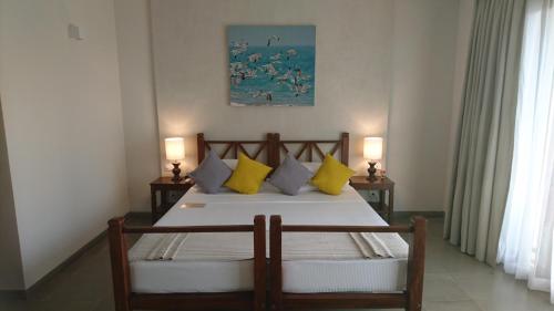 a bedroom with a bed with yellow and white pillows at The Palmyrah House in Mannar