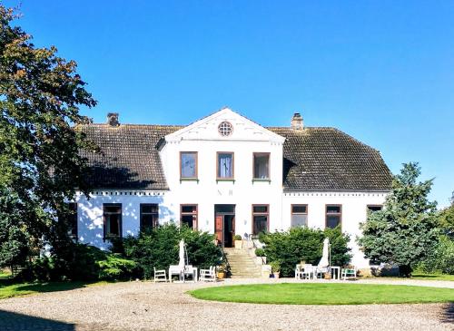 ein großes weißes Haus mit Tischen und Stühlen in der Unterkunft Feriengut Neuhof in Fehmarn