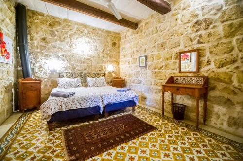 a bedroom with a bed in a stone walled room at "Steves Villas" Villa ta Rosi in Xagħra