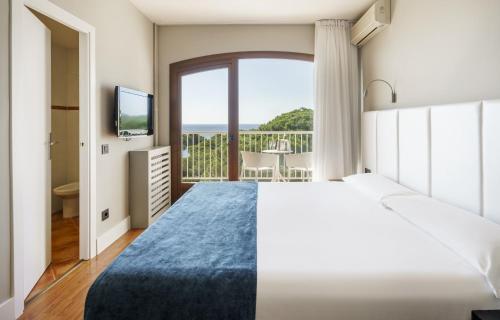 a bedroom with a large bed and a large window at Ilunion Caleta Park in Sant Feliu de Guíxols