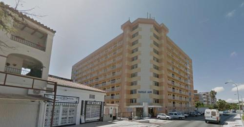 un edificio alto con coches estacionados frente a él en Saltillo Alto (El pinillo), en Torremolinos