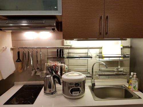 a kitchen counter top with a sink and a stove at Stay Amare Green La Salle Taft in Manila