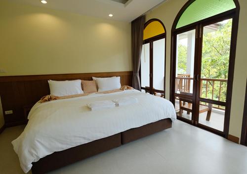a bedroom with a large bed and a balcony at Baan Imm Sook Resort in Chao Lao Beach
